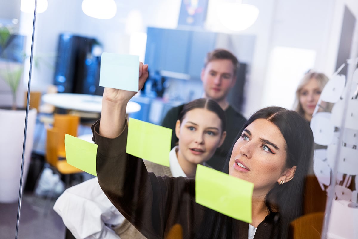 Girl puts post-it notes on glass wall